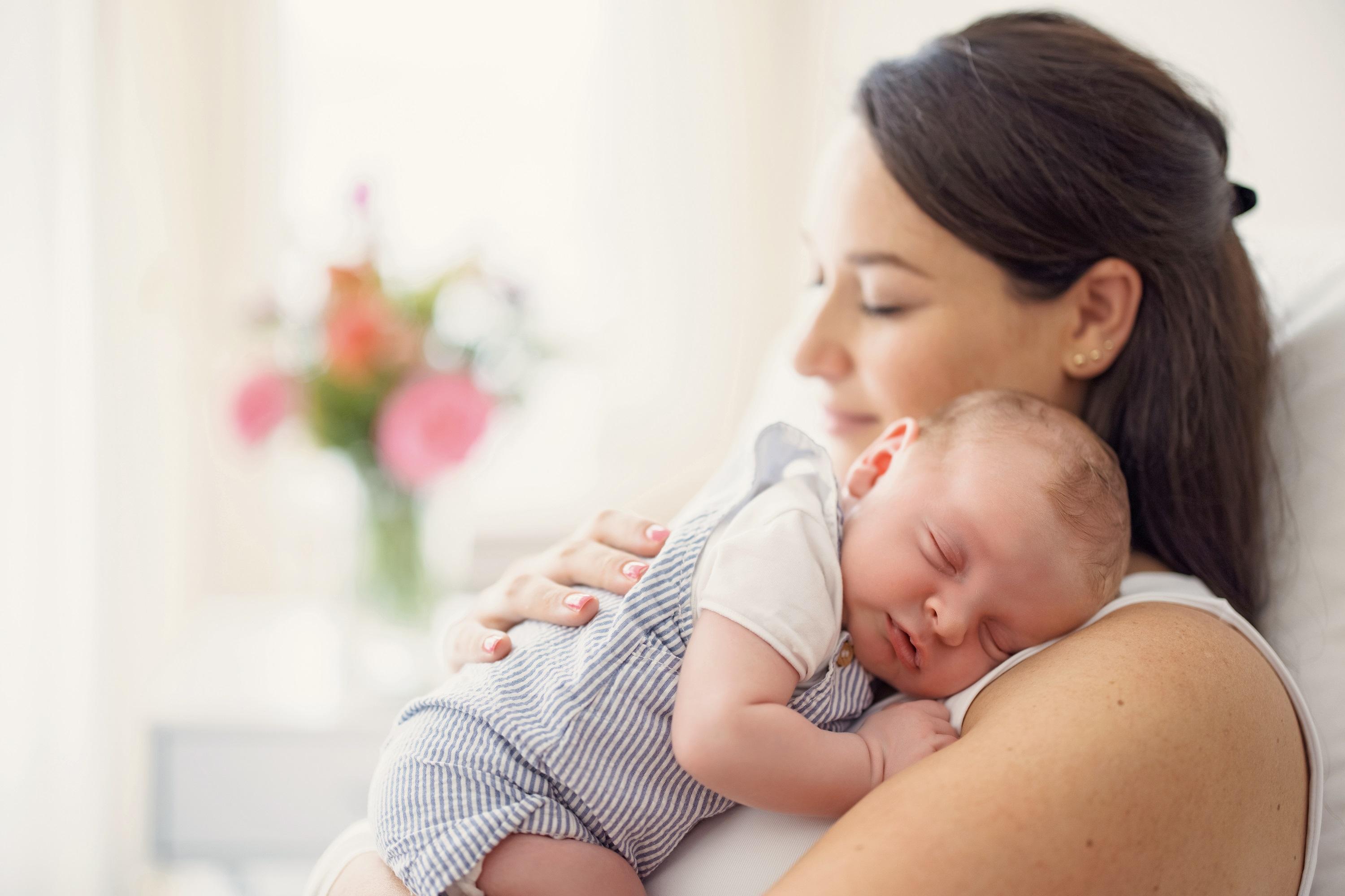 Eine liebevolle Mutter hält ihr schlafendes Baby im Arm.