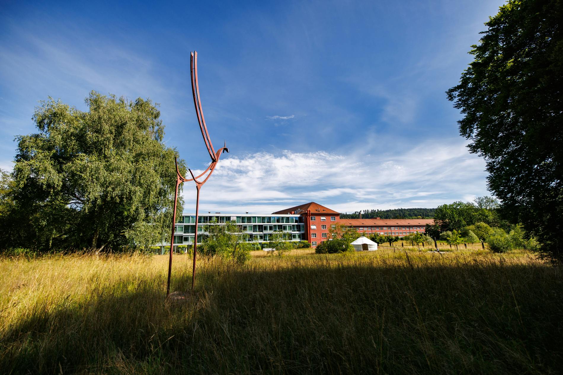 Moderne Architektur und Kunstinstallation im Grünen unter blauem Himmel.