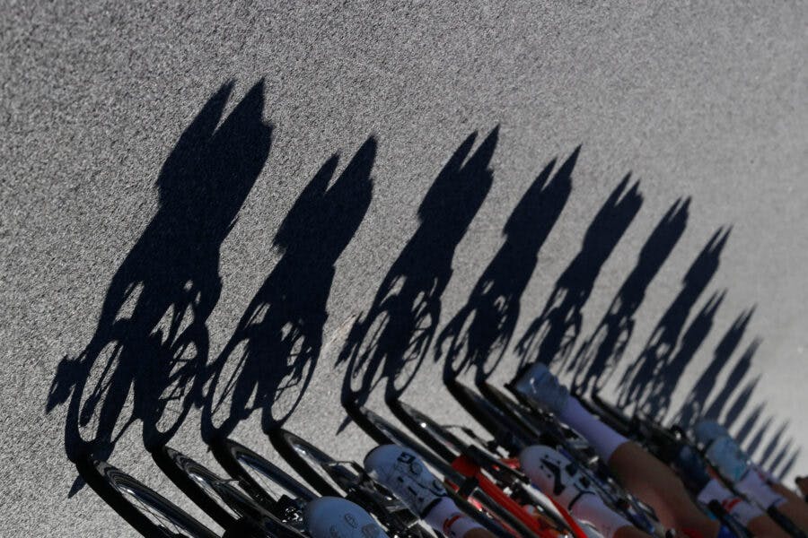 Schatten von Radfahrern auf Straße bei sonnigem Wetter.