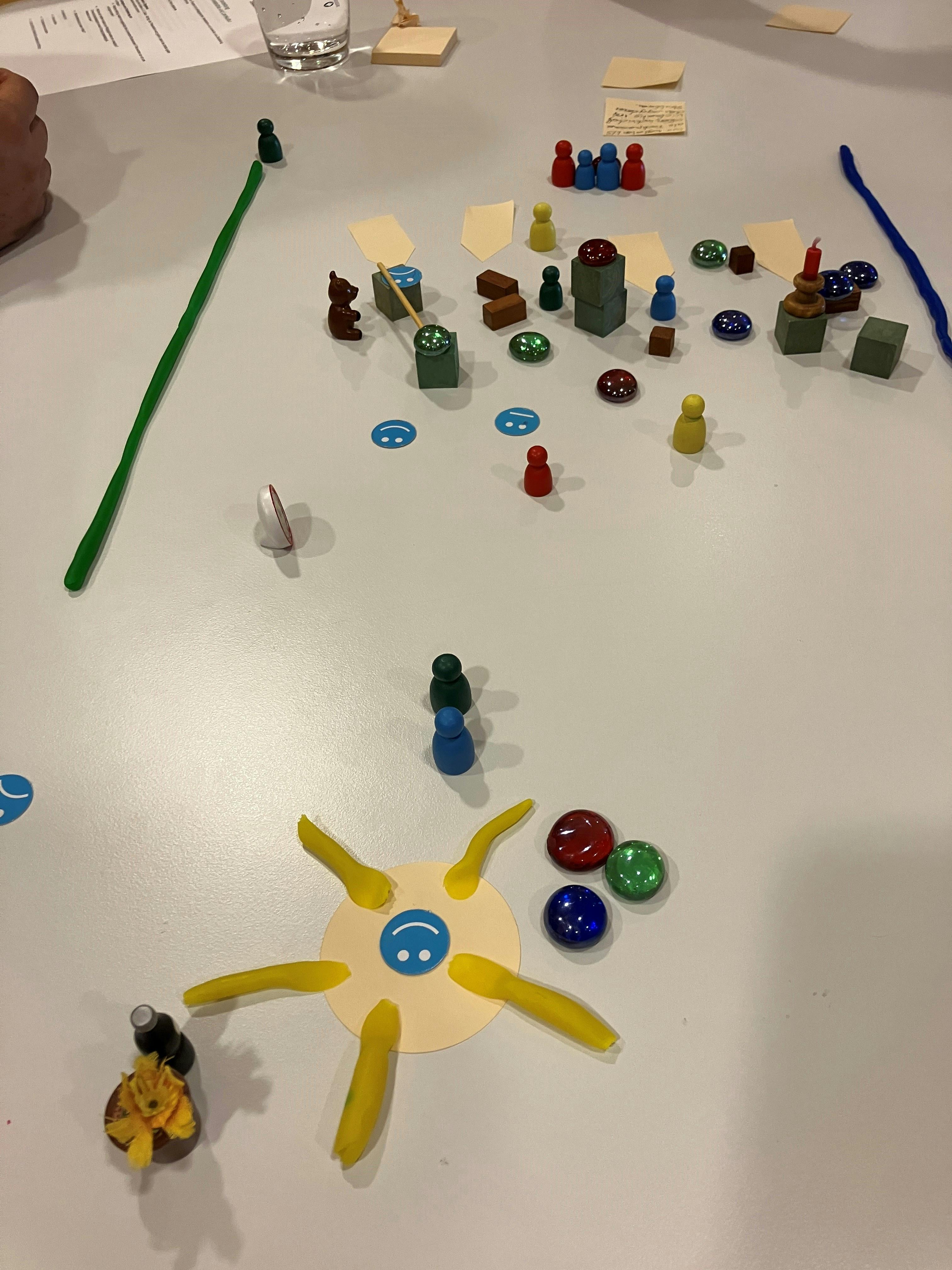 Brettspiel mit bunten Figuren und Spielsteinen auf weißer Oberfläche.