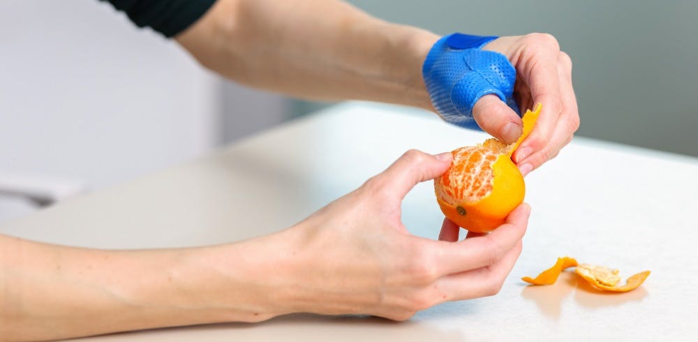 Person schält eine Mandarine mit einem Küchenhandschuh