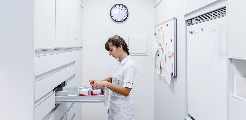 Krankenschwester bereitet Medikation in einem weißen, ordentlichen Behandlungsraum vor.