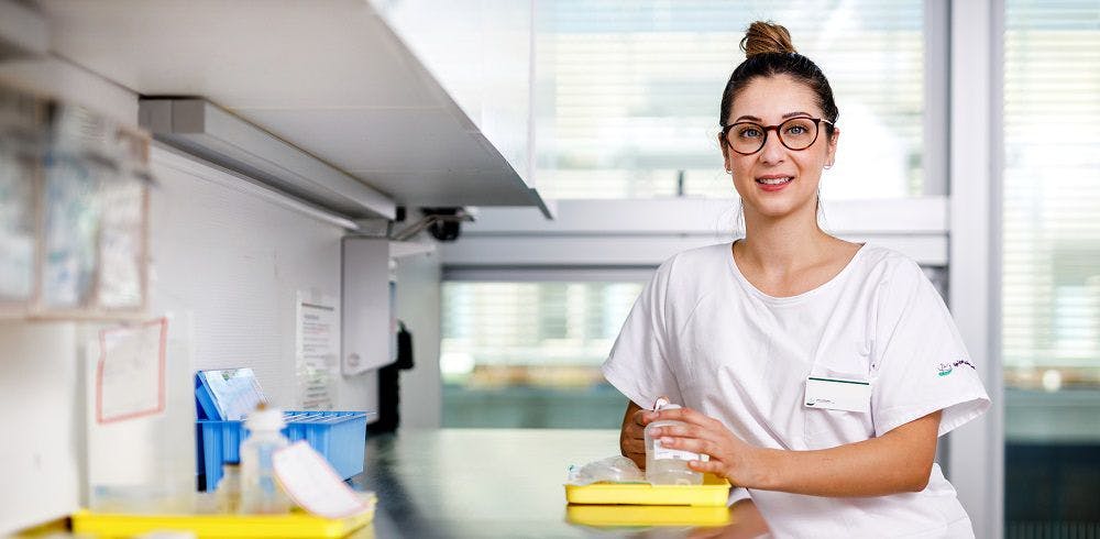 Lächelnde Krankenschwester mit Brille steht im Krankenhaus.