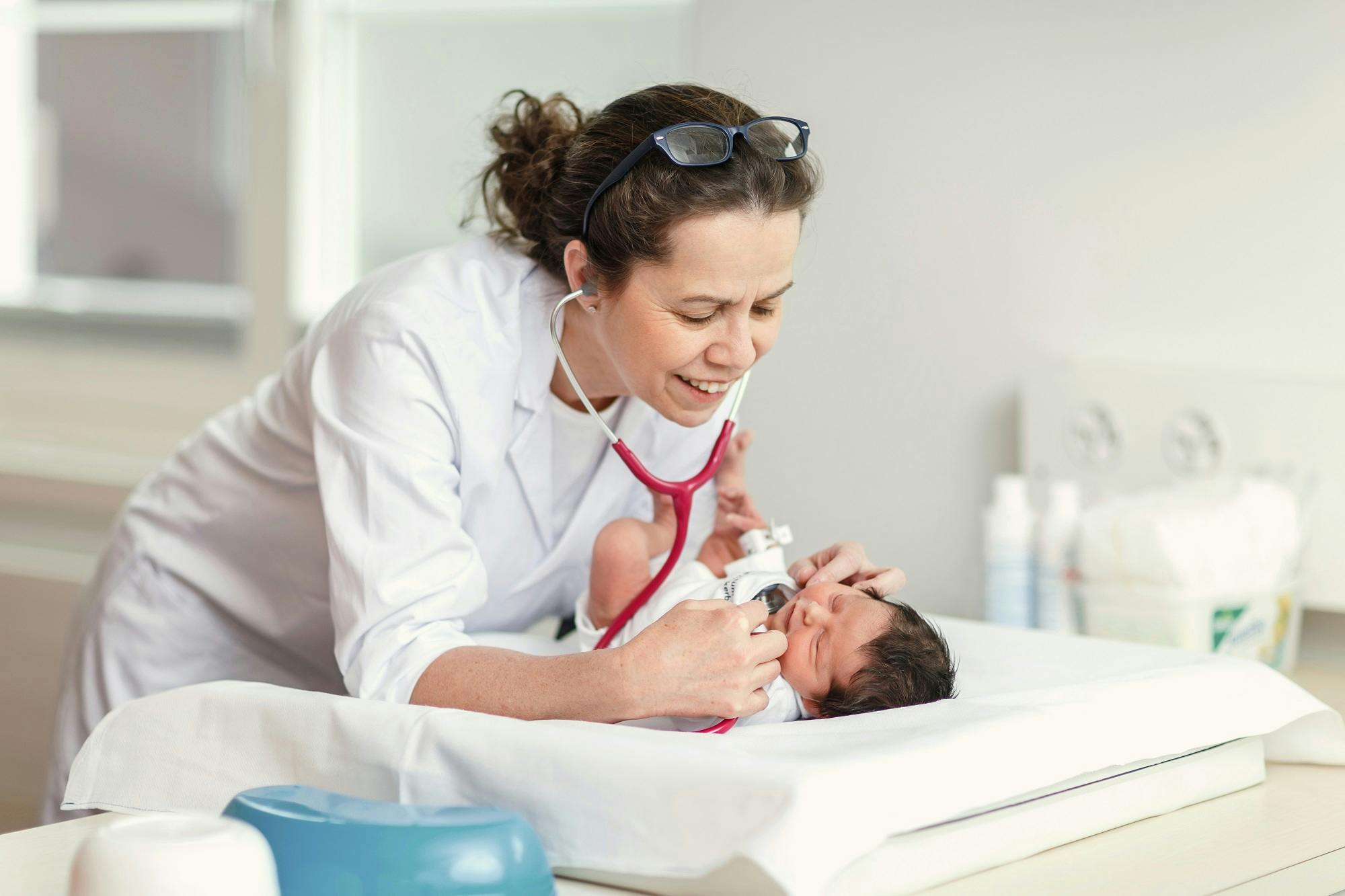 Kinderärztin untersucht Neugeborenes mit Stethoskop.