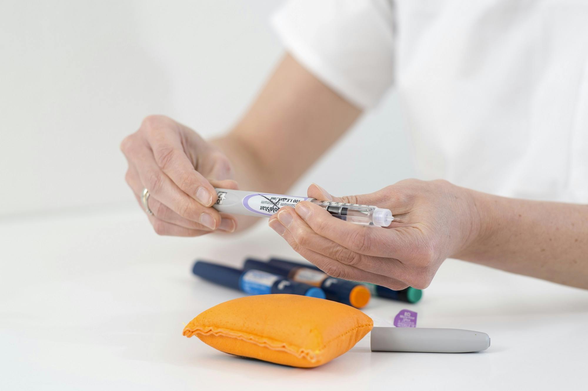 Ein Mediziner bereitet einen Insulinpen vor, mit weiteren Diabetes-Utensilien im Vordergrund.