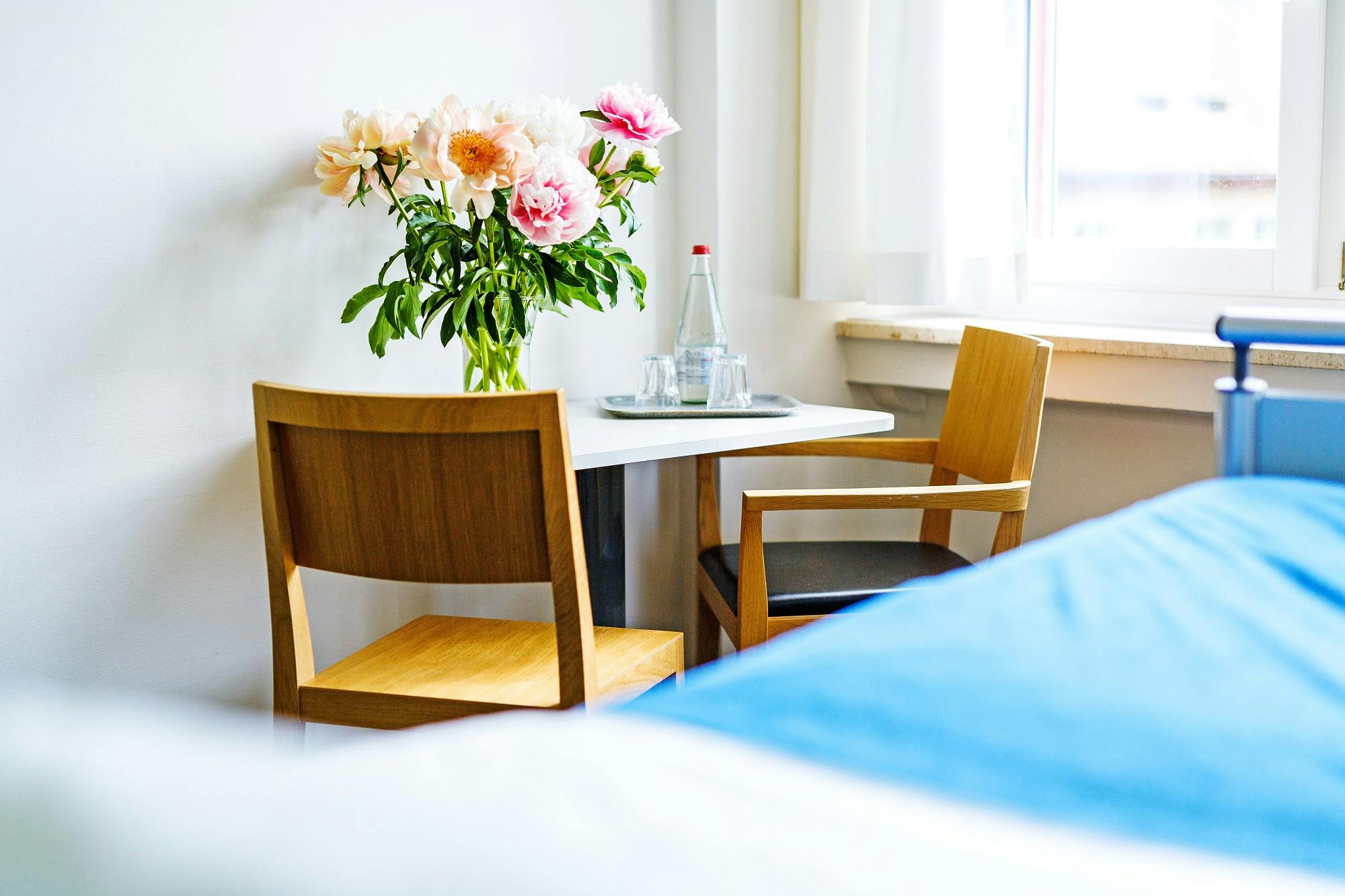 Helles Zimmer mit Blumenstrauß auf Tisch und modernen Holzstühlen.