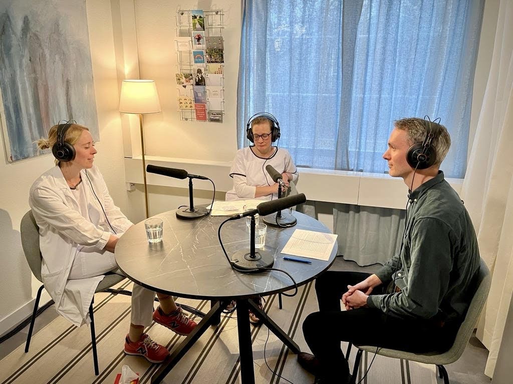 Drei Personen nehmen einen Podcast in einem hellen Raum auf.