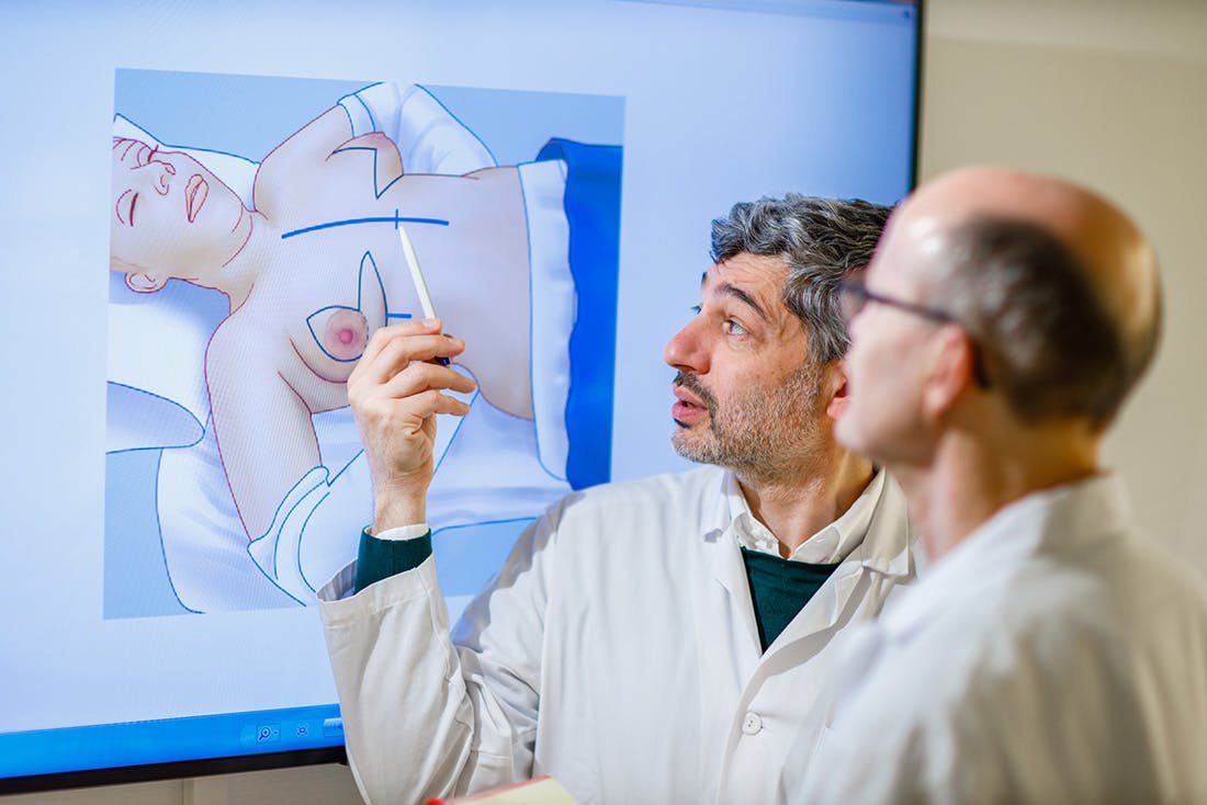 Zwei Mediziner betrachten und besprechen eine anatomische Darstellung auf einem Bildschirm.