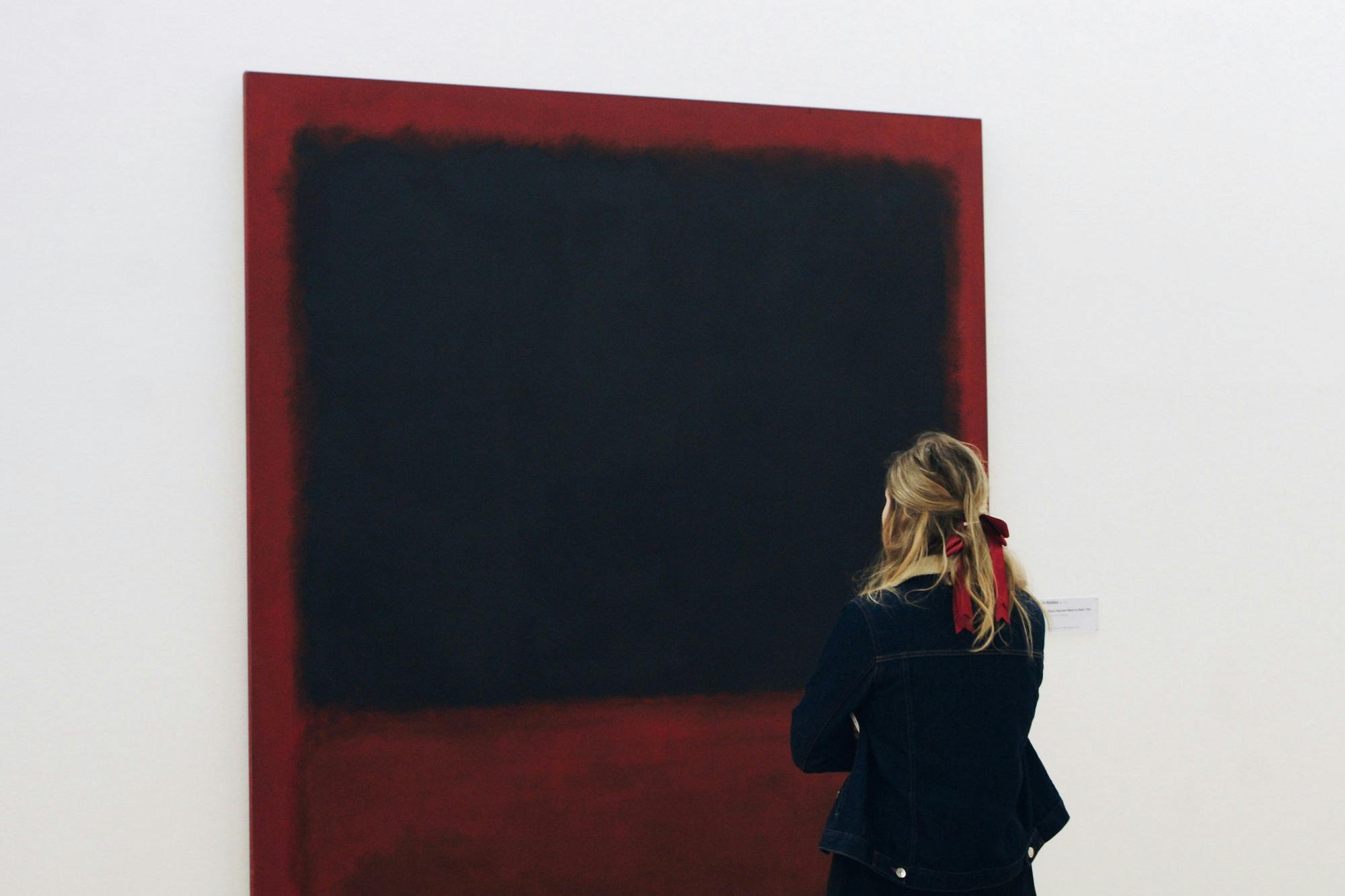Frau betrachtet ein großes abstraktes Gemälde in einer Galerie.